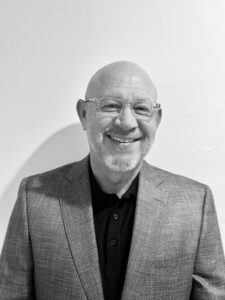 a black and white image of a bald man in a suit jacket